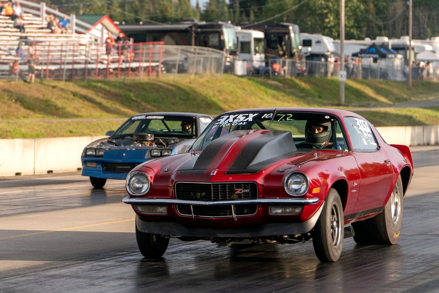 A red Camaro and a blue Camaro running head to head down the quarter mile.