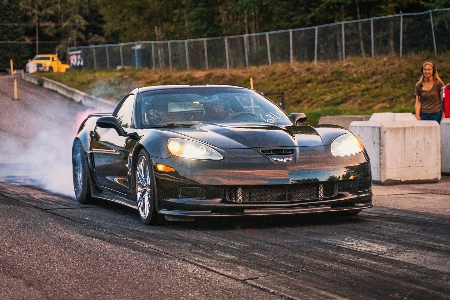 A black Corvette doing a smoking burnout in the water box at NITRO Motorsports Park.